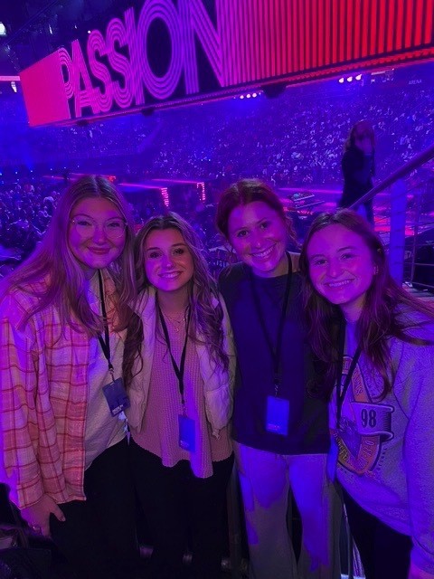 Four young women from Hope Church smiling for a photo in front of the Passion stage
