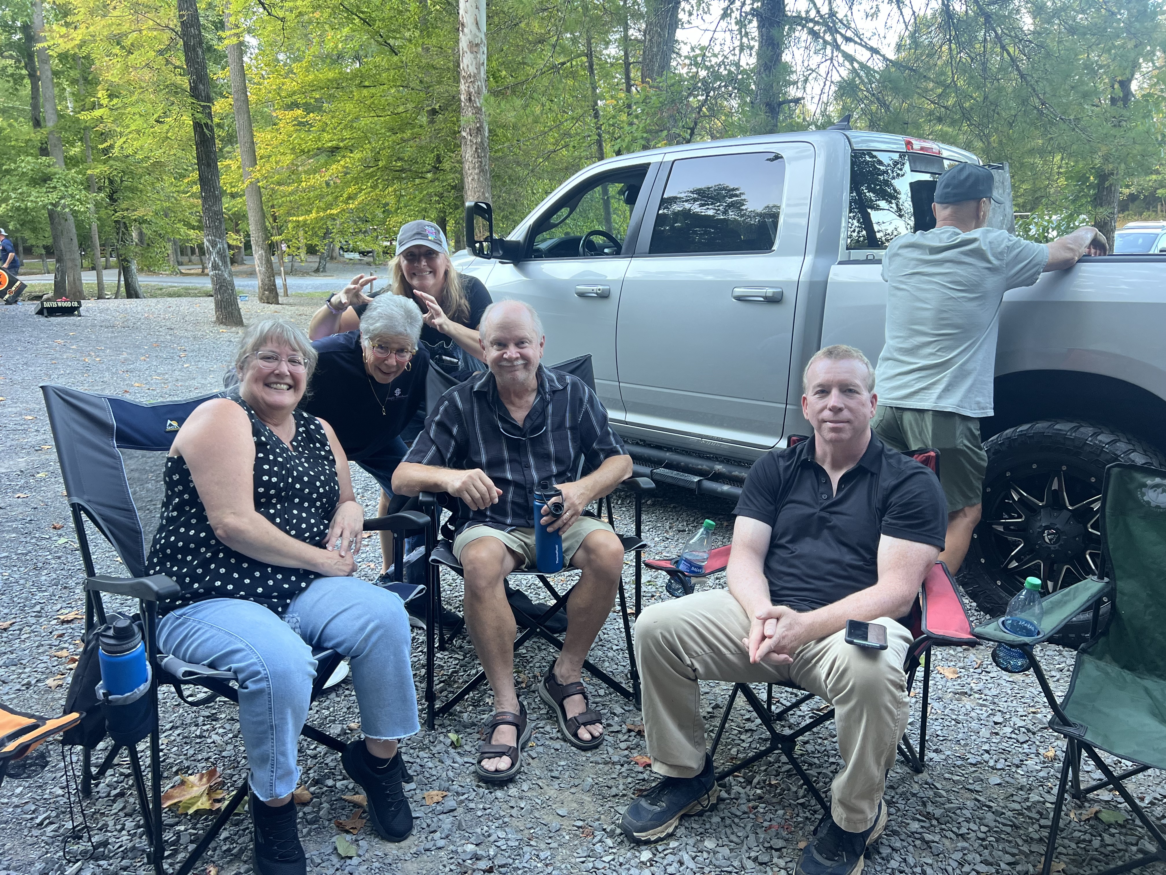 The Fueled by Hope group gathered around a long table for a potluck by the creek, sharing a meal together on a sunny afternoon