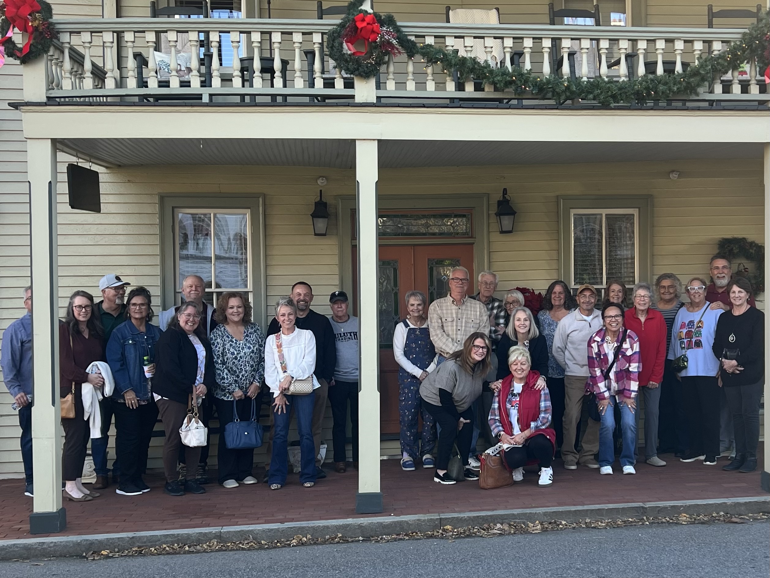 Large group of Fueled by Hope members posed together on a decorated front porch during a Christmas outing in Jonesborough