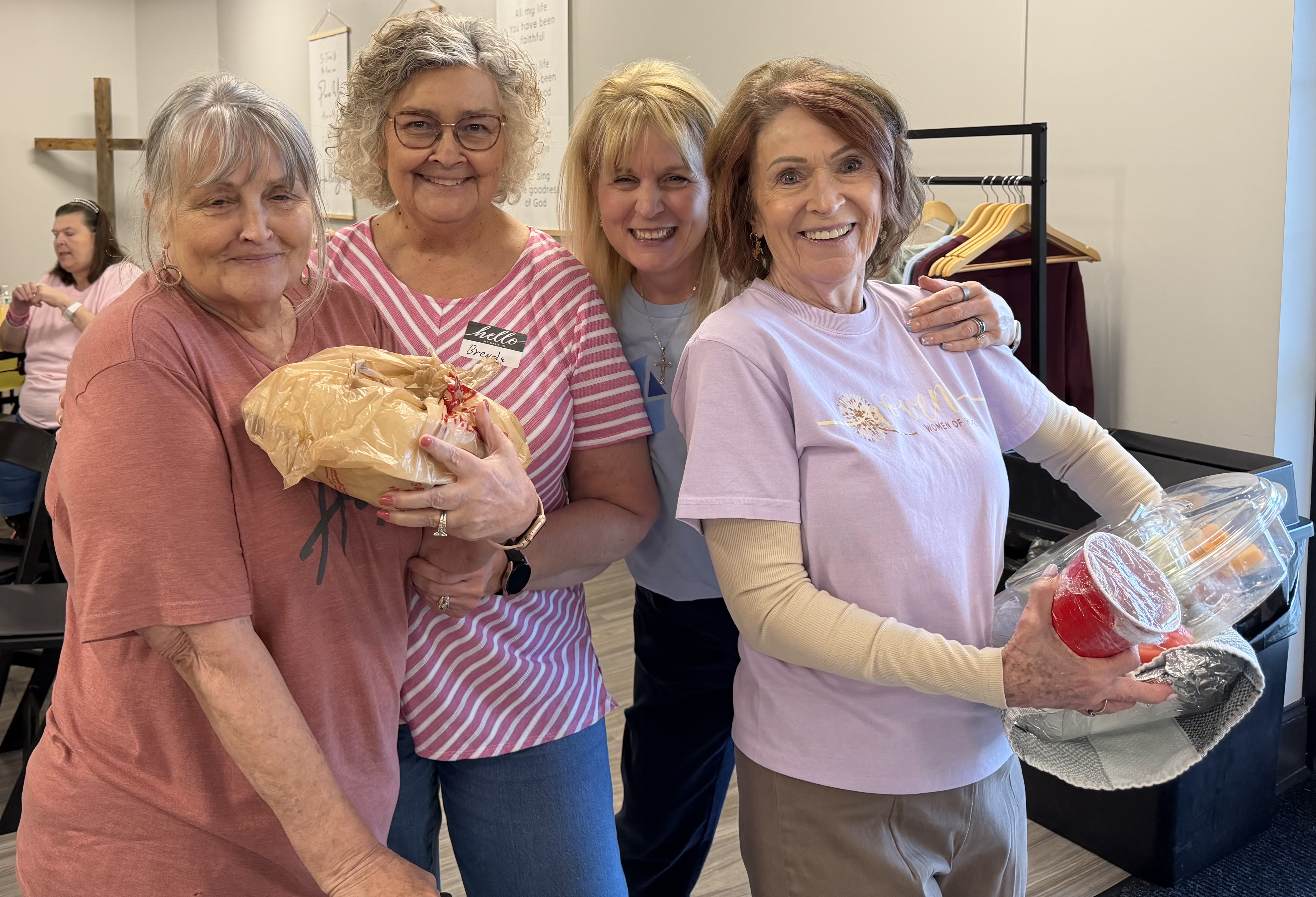 Four women holding wrapped meals and dishes, getting ready to deliver them to neighbors as part of a Fueled by Hope outreach