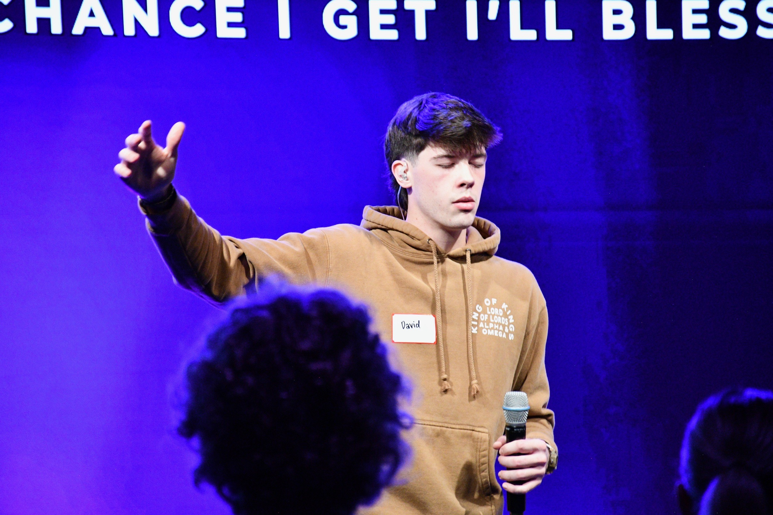 A Hope Students worship leader on stage with arm raised