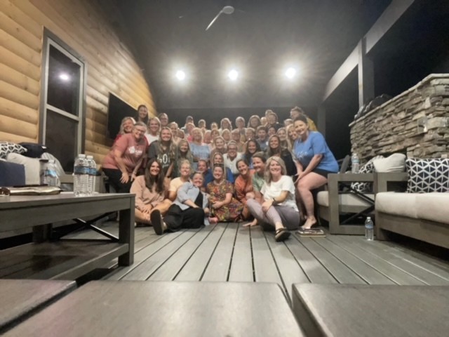 The Woven women's retreat group gathered together on a cabin porch at night
